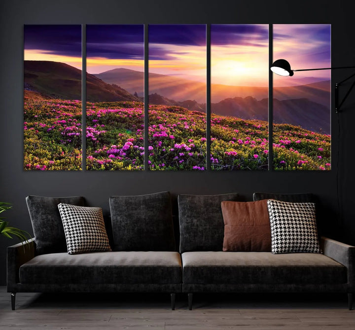 A living room showcases the Beautiful Mountain Sunset Landscape with Purple Flowers Canvas Wall Art Print, featuring a triptych of a vibrant sunset over mountains and blooming flowers, vividly rendered on museum-quality canvas with UV-protective coating.