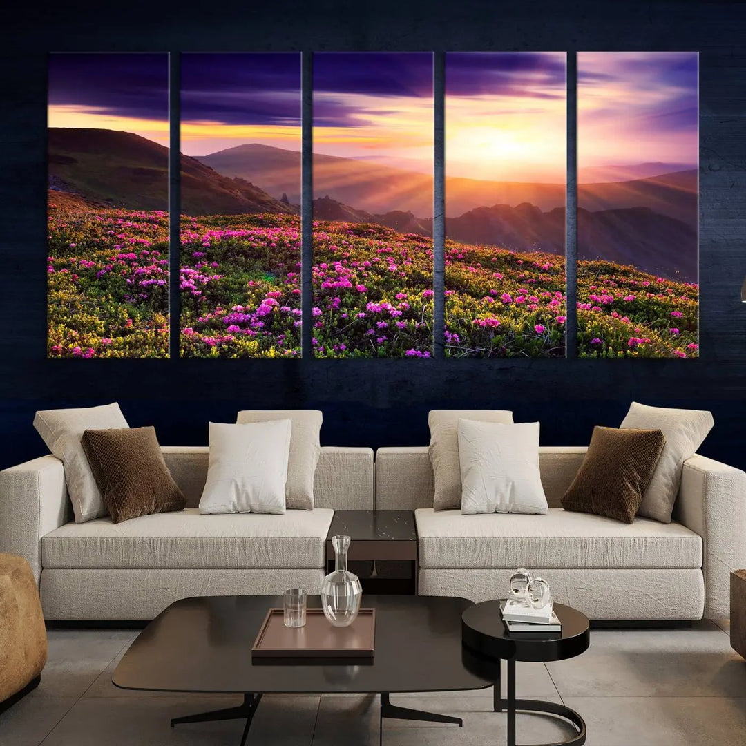 A living room showcases the Beautiful Mountain Sunset Landscape with Purple Flowers Canvas Wall Art Print, featuring a triptych of a vibrant sunset over mountains and blooming flowers, vividly rendered on museum-quality canvas with UV-protective coating.