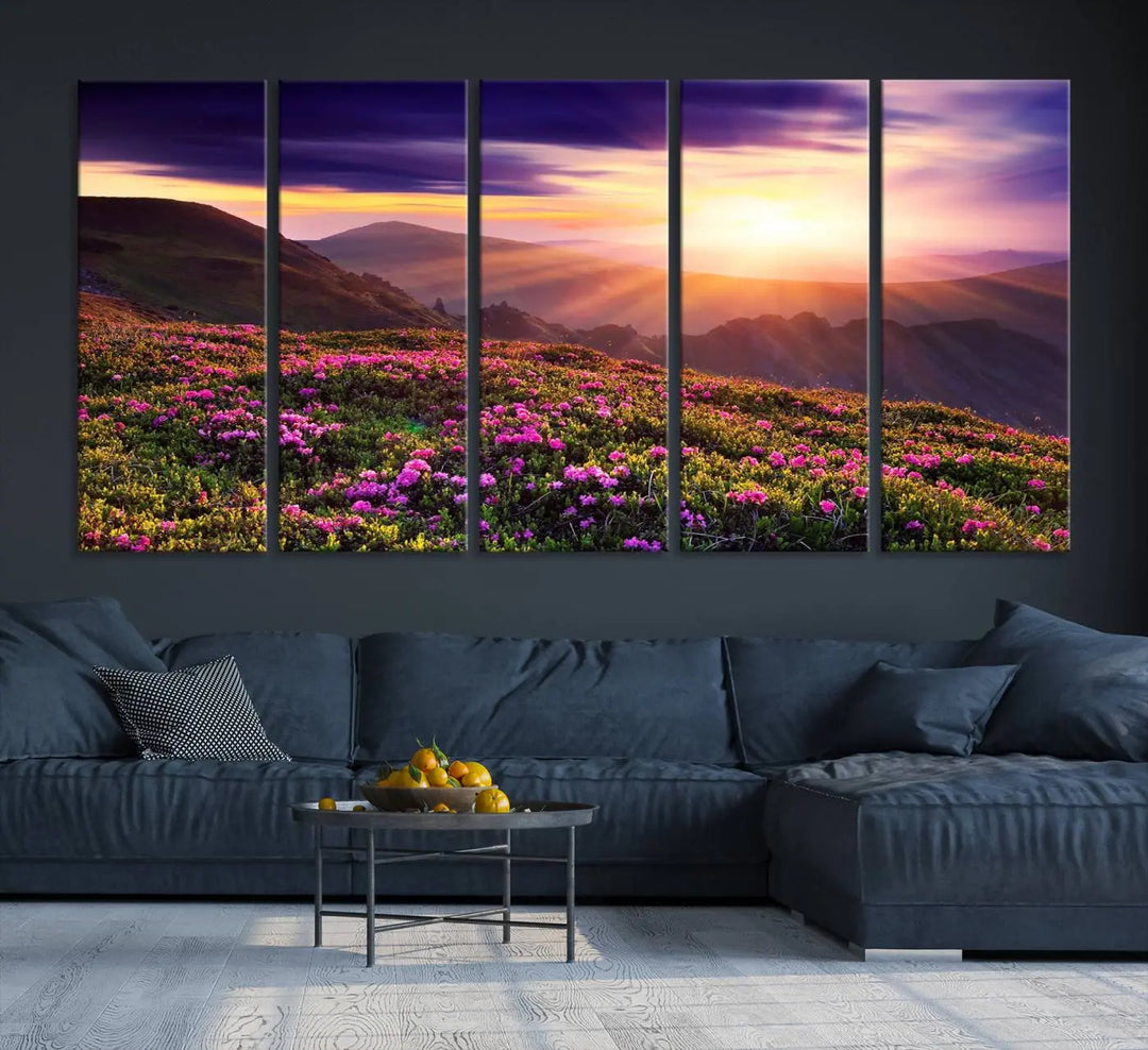 A living room showcases the Beautiful Mountain Sunset Landscape with Purple Flowers Canvas Wall Art Print, featuring a triptych of a vibrant sunset over mountains and blooming flowers, vividly rendered on museum-quality canvas with UV-protective coating.