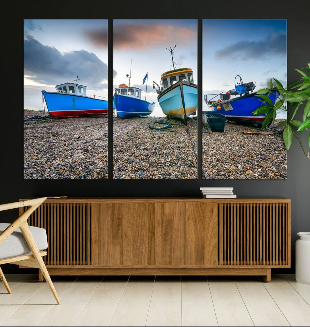 The "Big Boats On The Beach Wall Art Canvas Print" is a stunning piece featuring three museum-quality panels depicting fishing boats on a pebbled shore. Ready to hang and featuring UV-protective coating, it serves as an elegant addition to your home décor.