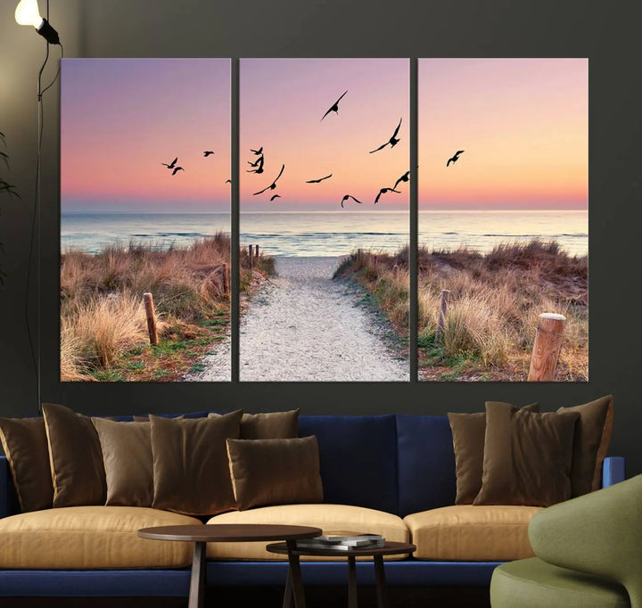 The "Birds on the Beach Sunset Wall Art Canvas Print" showcases a serene scene of seagulls soaring over a beach path at sunrise, beautifully capturing the endless sea and sky.