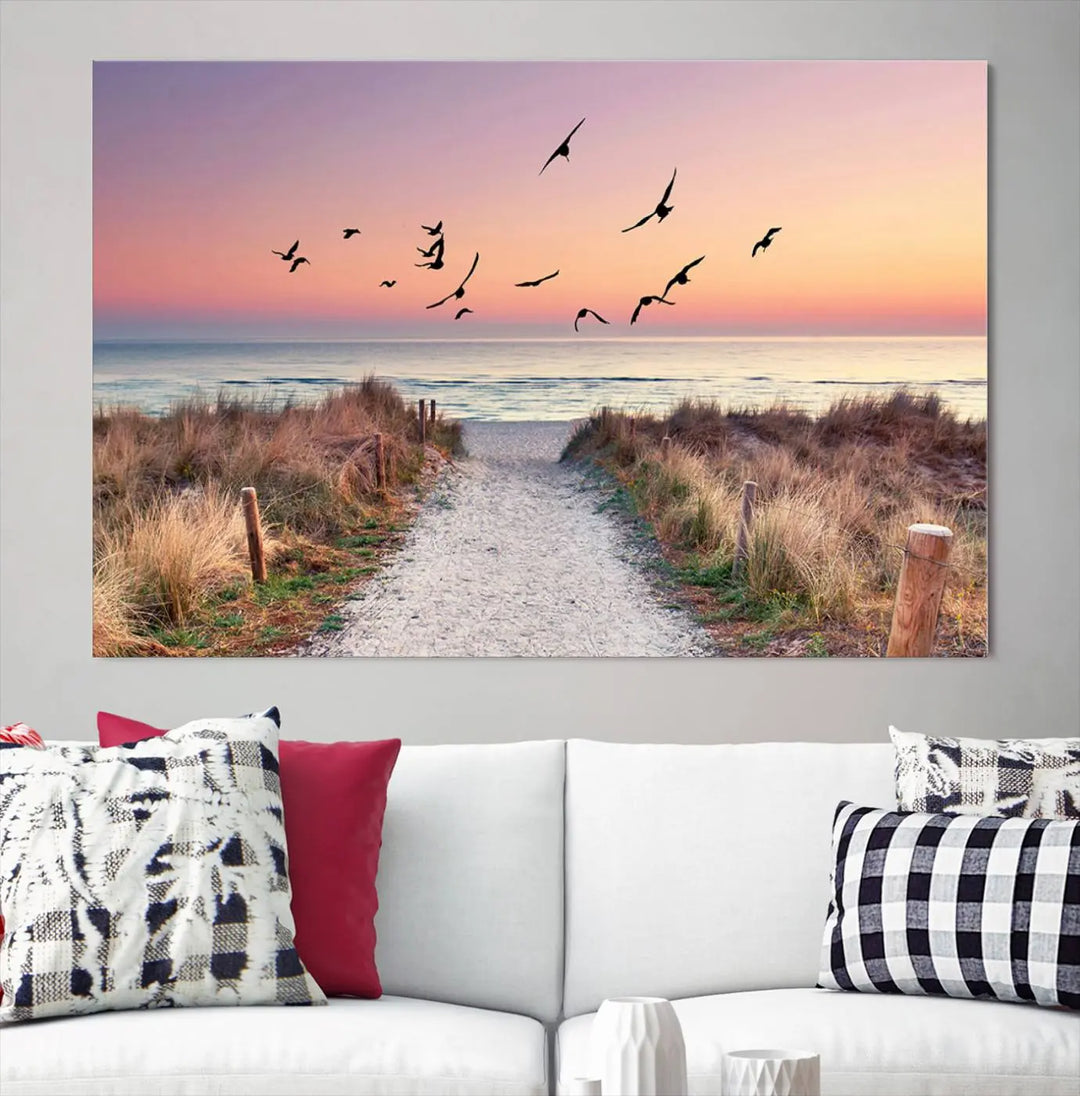 The "Birds on the Beach Sunset Wall Art Canvas Print" showcases a serene scene of seagulls soaring over a beach path at sunrise, beautifully capturing the endless sea and sky.