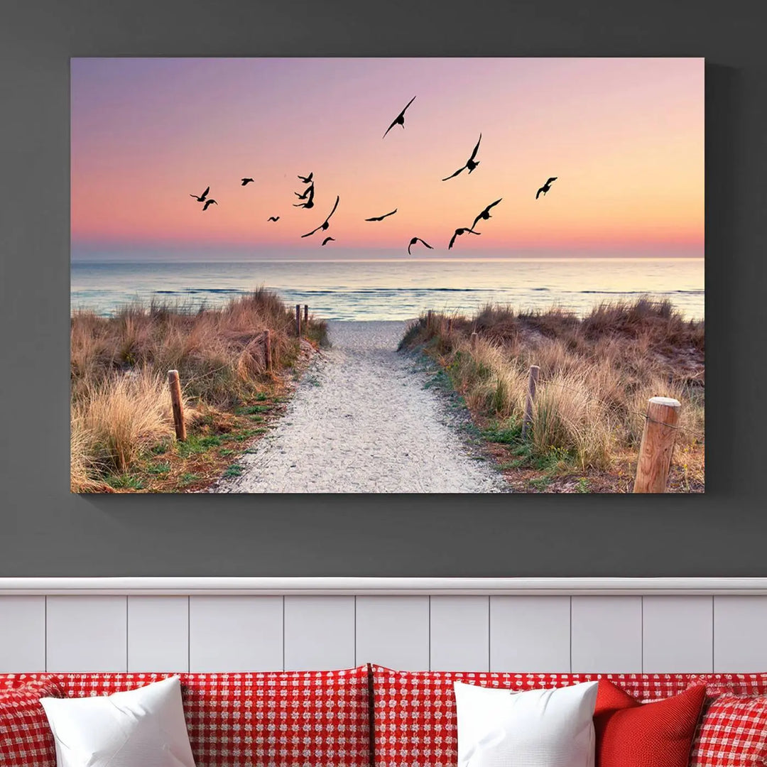 The "Birds on the Beach Sunset Wall Art Canvas Print" showcases a serene scene of seagulls soaring over a beach path at sunrise, beautifully capturing the endless sea and sky.