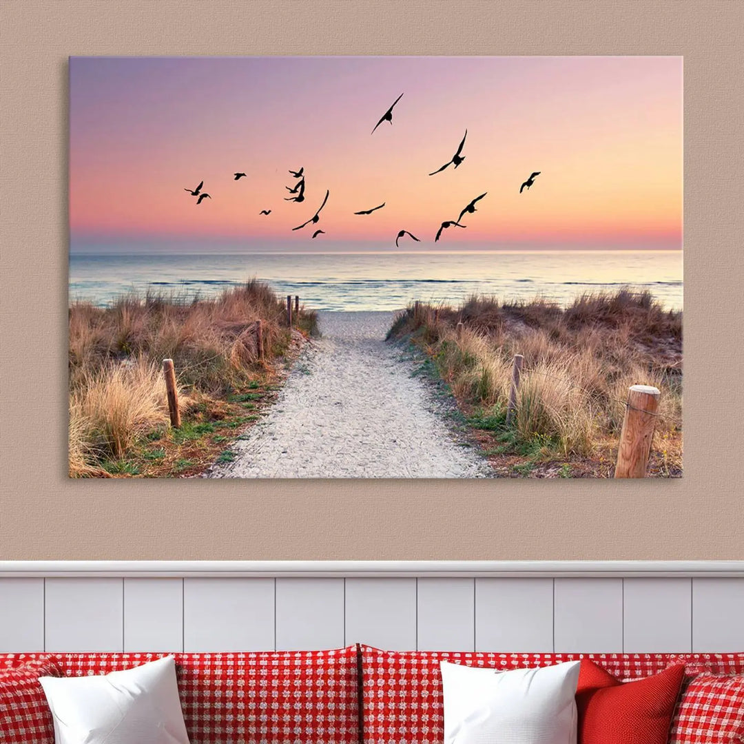 The "Birds on the Beach Sunset Wall Art Canvas Print" showcases a serene scene of seagulls soaring over a beach path at sunrise, beautifully capturing the endless sea and sky.