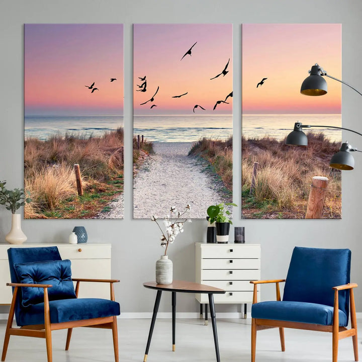 The "Birds on the Beach Sunset Wall Art Canvas Print" showcases a serene scene of seagulls soaring over a beach path at sunrise, beautifully capturing the endless sea and sky.