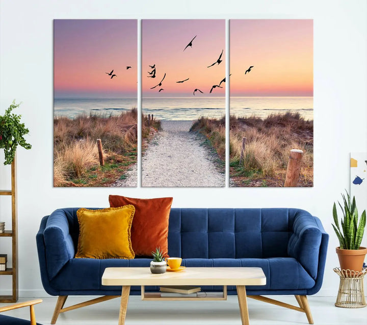 The "Birds on the Beach Sunset Wall Art Canvas Print" showcases a serene scene of seagulls soaring over a beach path at sunrise, beautifully capturing the endless sea and sky.