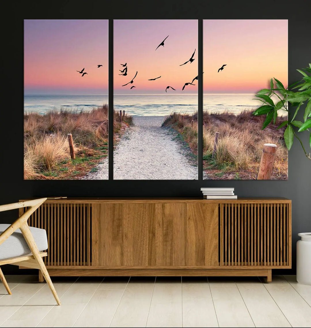 The "Birds on the Beach Sunset Wall Art Canvas Print" showcases a serene scene of seagulls soaring over a beach path at sunrise, beautifully capturing the endless sea and sky.