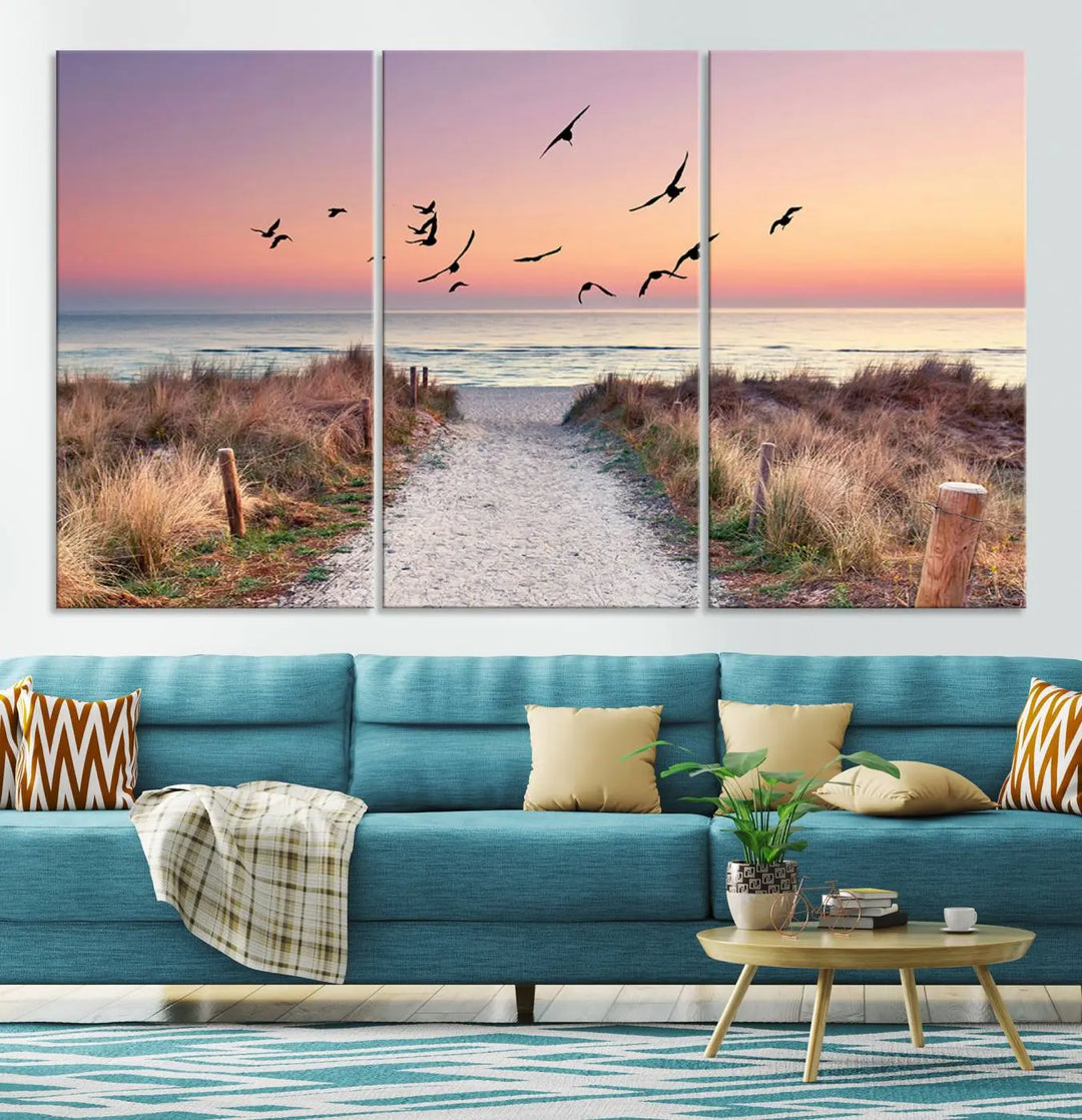 The "Birds on the Beach Sunset Wall Art Canvas Print" showcases a serene scene of seagulls soaring over a beach path at sunrise, beautifully capturing the endless sea and sky.