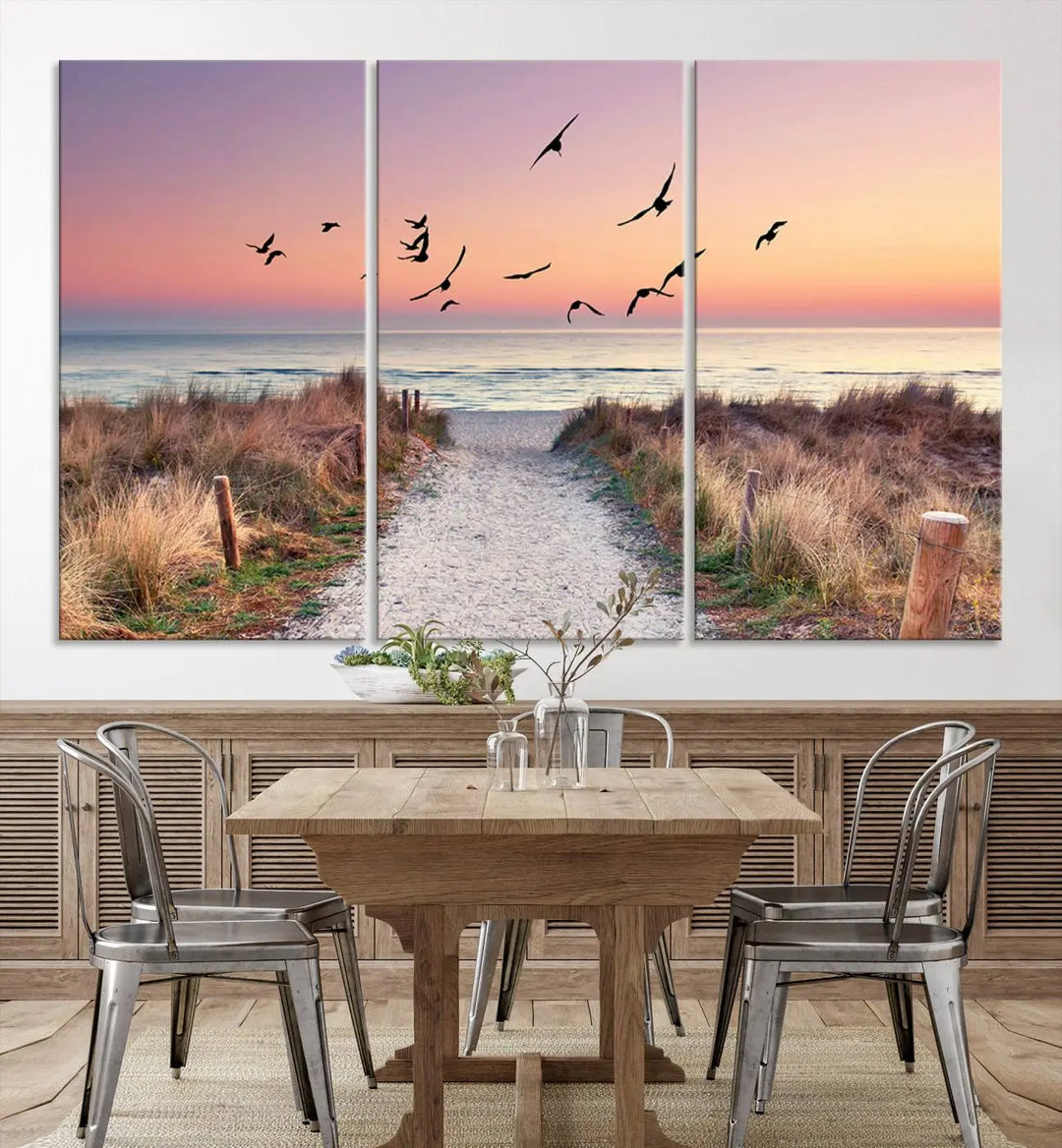 The "Birds on the Beach Sunset Wall Art Canvas Print" showcases a serene scene of seagulls soaring over a beach path at sunrise, beautifully capturing the endless sea and sky.