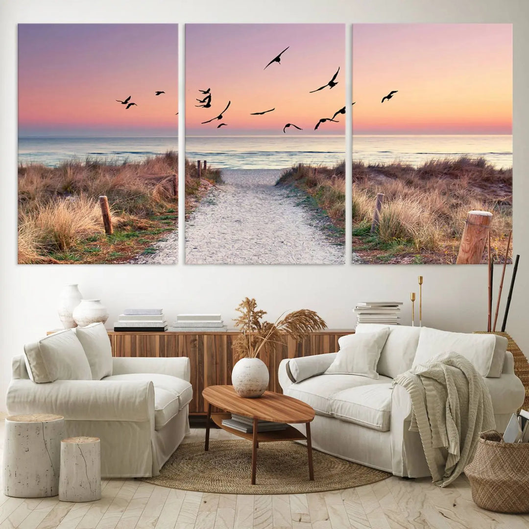 The "Birds on the Beach Sunset Wall Art Canvas Print" showcases a serene scene of seagulls soaring over a beach path at sunrise, beautifully capturing the endless sea and sky.