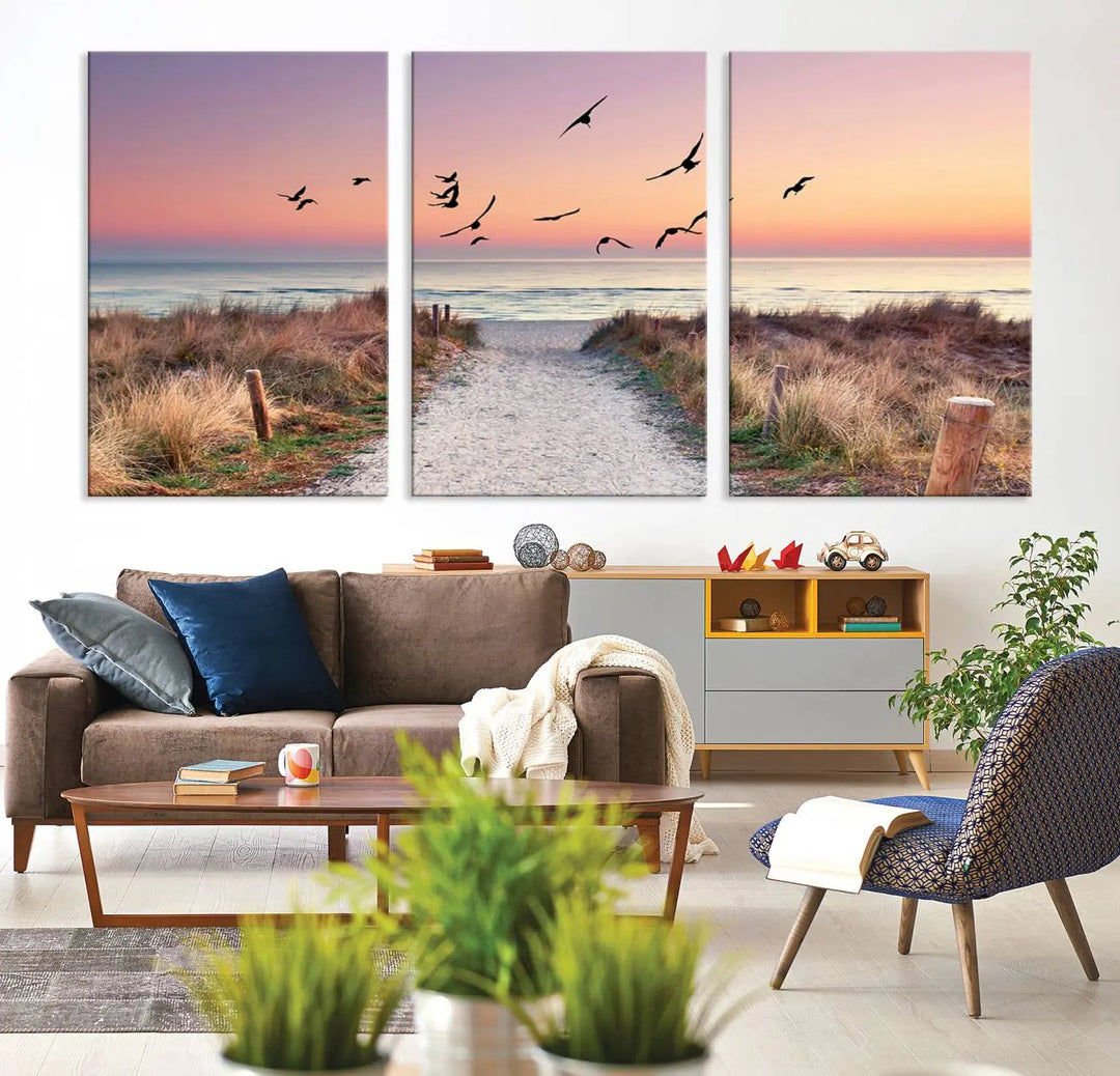 The "Birds on the Beach Sunset Wall Art Canvas Print" showcases a serene scene of seagulls soaring over a beach path at sunrise, beautifully capturing the endless sea and sky.