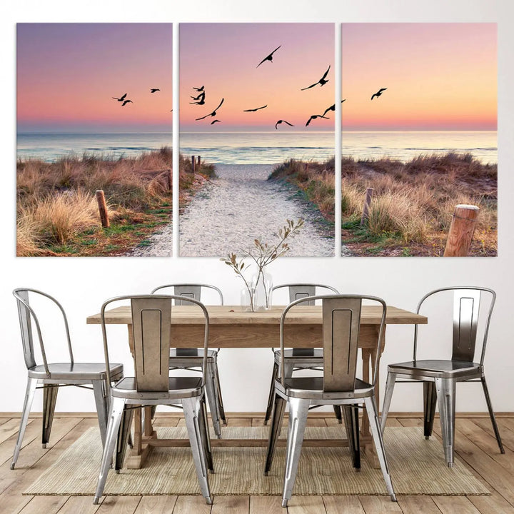 The "Birds on the Beach Sunset Wall Art Canvas Print" showcases a serene scene of seagulls soaring over a beach path at sunrise, beautifully capturing the endless sea and sky.