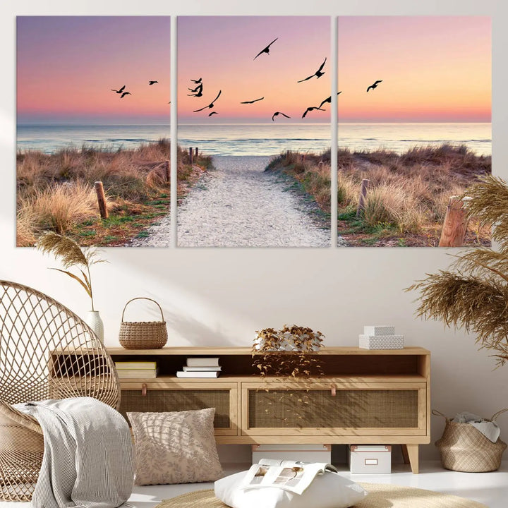 The "Birds on the Beach Sunset Wall Art Canvas Print" showcases a serene scene of seagulls soaring over a beach path at sunrise, beautifully capturing the endless sea and sky.