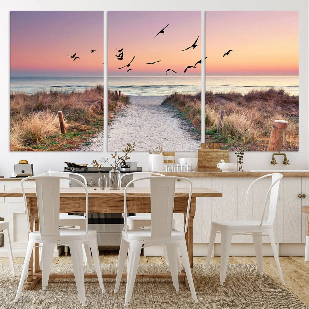 The "Birds on the Beach Sunset Wall Art Canvas Print" showcases a serene scene of seagulls soaring over a beach path at sunrise, beautifully capturing the endless sea and sky.