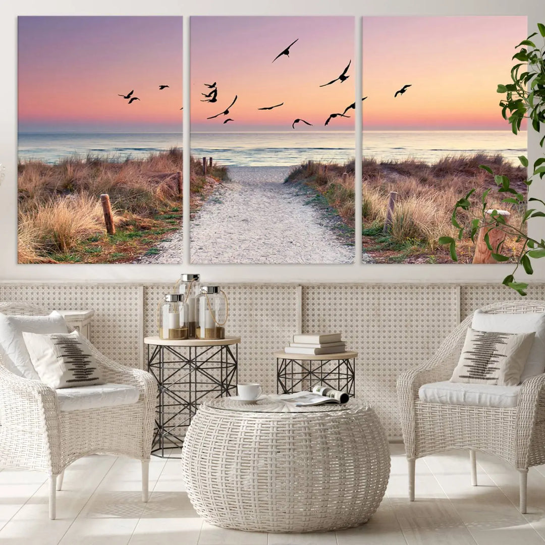 The "Birds on the Beach Sunset Wall Art Canvas Print" showcases a serene scene of seagulls soaring over a beach path at sunrise, beautifully capturing the endless sea and sky.