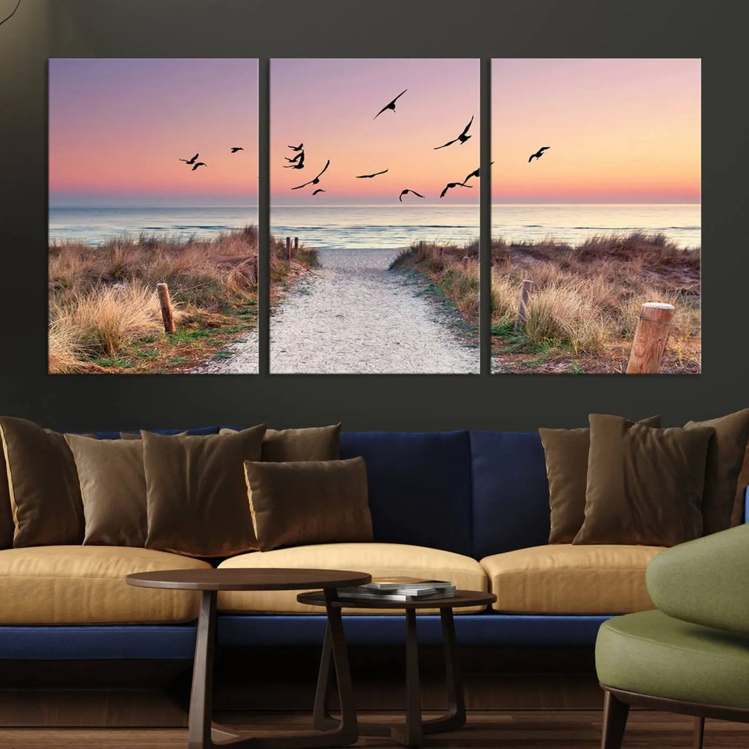 The "Birds on the Beach Sunset Wall Art Canvas Print" showcases a serene scene of seagulls soaring over a beach path at sunrise, beautifully capturing the endless sea and sky.