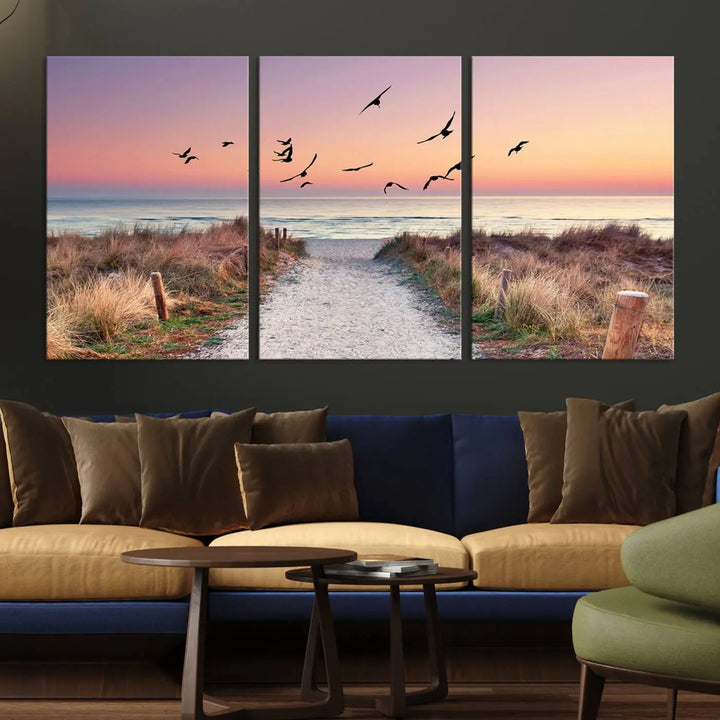 The "Birds on the Beach Sunset Wall Art Canvas Print" showcases a serene scene of seagulls soaring over a beach path at sunrise, beautifully capturing the endless sea and sky.