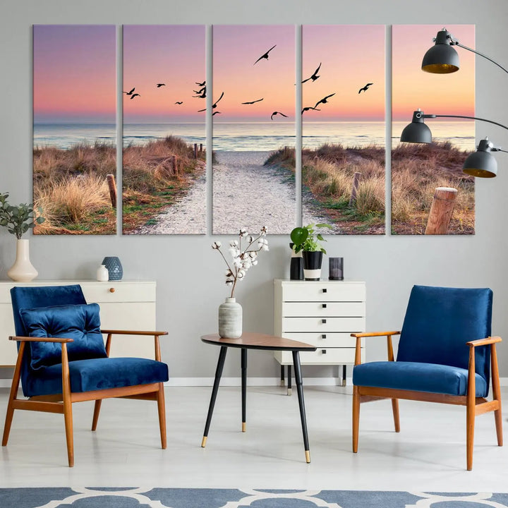 The "Birds on the Beach Sunset Wall Art Canvas Print" showcases a serene scene of seagulls soaring over a beach path at sunrise, beautifully capturing the endless sea and sky.