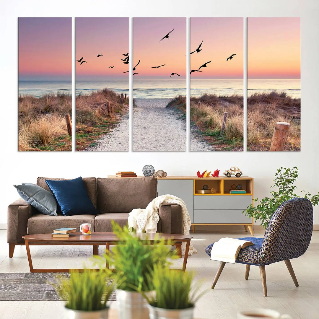 The "Birds on the Beach Sunset Wall Art Canvas Print" showcases a serene scene of seagulls soaring over a beach path at sunrise, beautifully capturing the endless sea and sky.