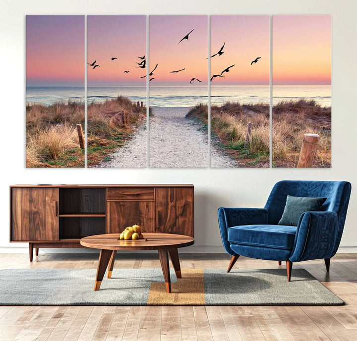 The "Birds on the Beach Sunset Wall Art Canvas Print" showcases a serene scene of seagulls soaring over a beach path at sunrise, beautifully capturing the endless sea and sky.