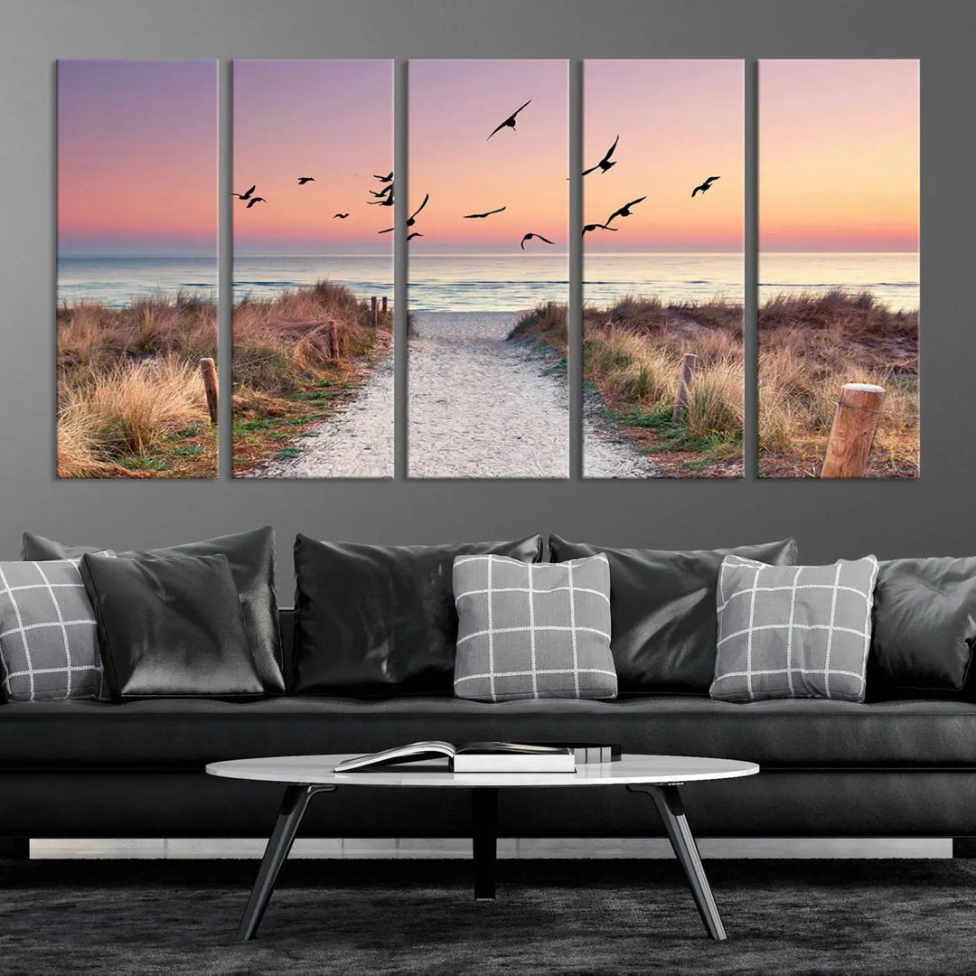 The "Birds on the Beach Sunset Wall Art Canvas Print" showcases a serene scene of seagulls soaring over a beach path at sunrise, beautifully capturing the endless sea and sky.