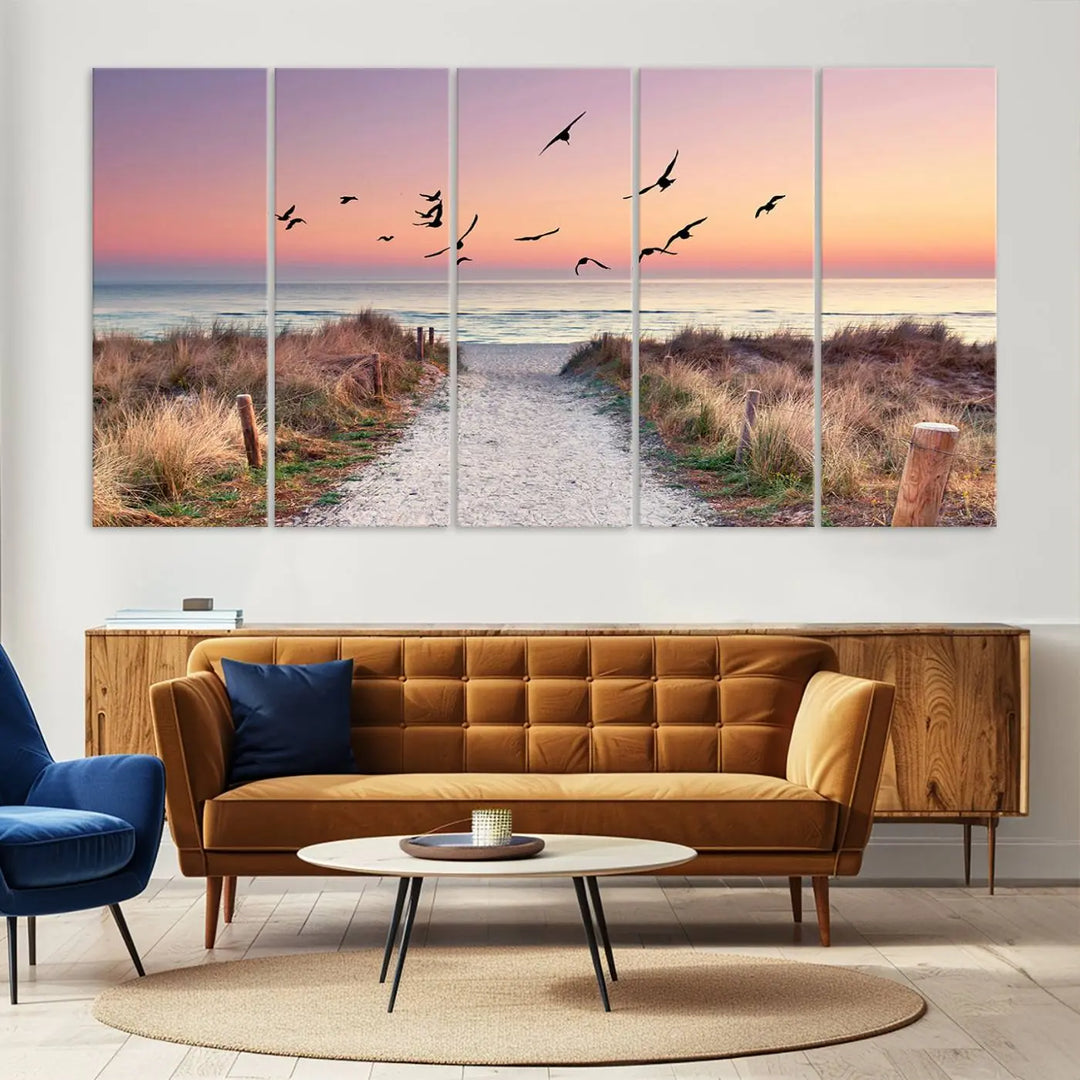 The "Birds on the Beach Sunset Wall Art Canvas Print" showcases a serene scene of seagulls soaring over a beach path at sunrise, beautifully capturing the endless sea and sky.