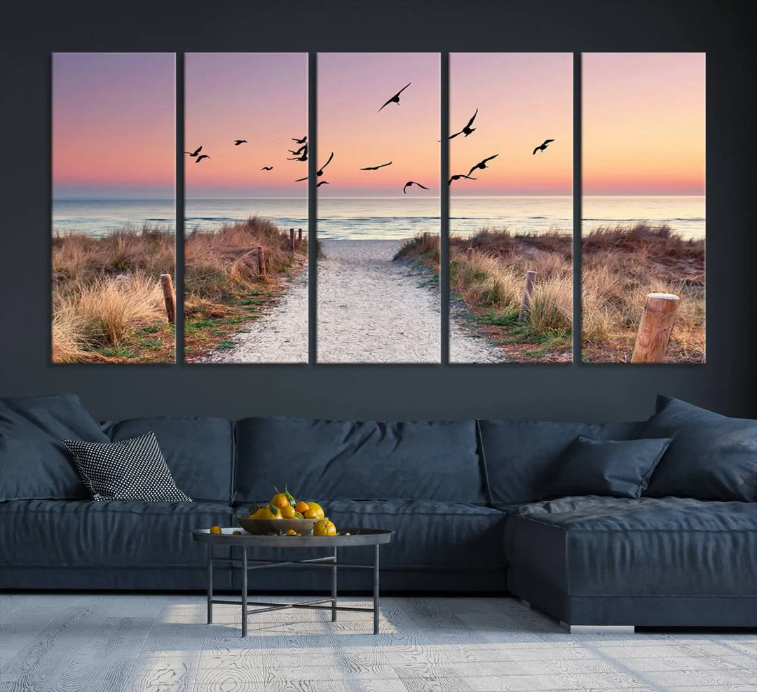 The "Birds on the Beach Sunset Wall Art Canvas Print" showcases a serene scene of seagulls soaring over a beach path at sunrise, beautifully capturing the endless sea and sky.