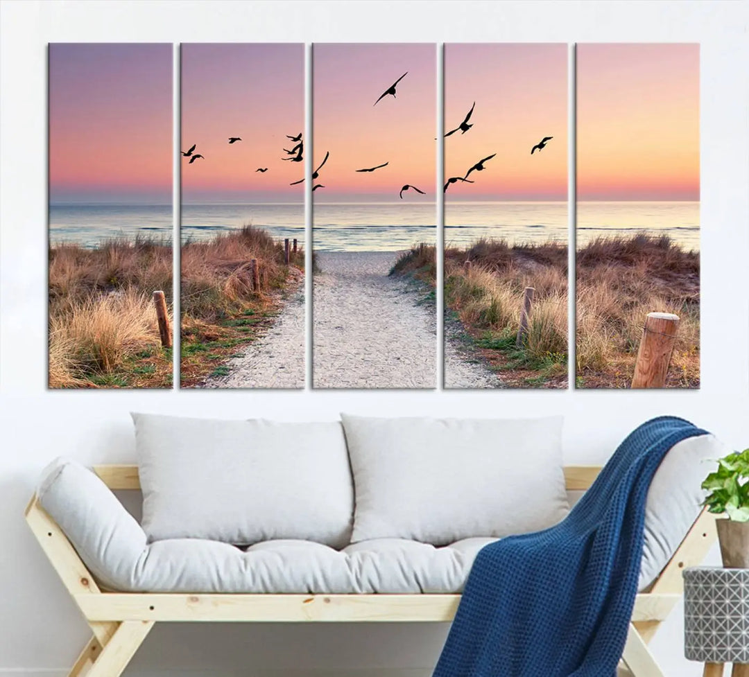 The "Birds on the Beach Sunset Wall Art Canvas Print" showcases a serene scene of seagulls soaring over a beach path at sunrise, beautifully capturing the endless sea and sky.