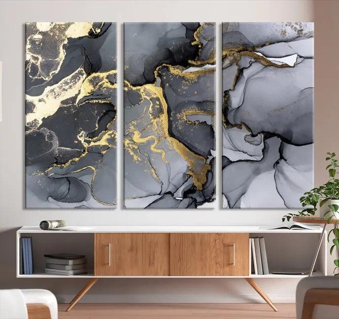 The Black Marble Fluid Effect Wall Art Abstract Canvas Wall Art Print features a triptych of black, gray, and gold abstract designs on museum-quality canvas. This elegant piece is ready to hang and includes a UV-protective coating to ensure its enduring allure.