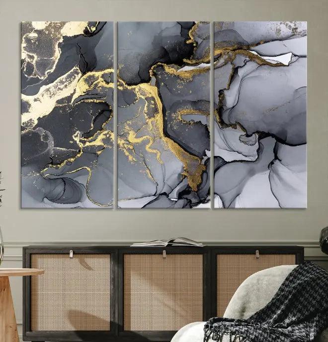 The Black Marble Fluid Effect Wall Art Abstract Canvas Wall Art Print features a triptych of black, gray, and gold abstract designs on museum-quality canvas. This elegant piece is ready to hang and includes a UV-protective coating to ensure its enduring allure.