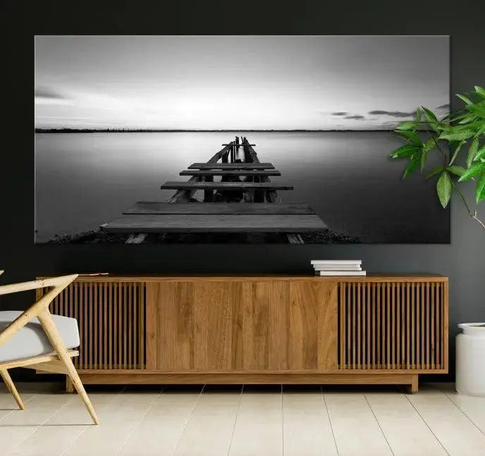 Titled "Black & White Old Wooden Pier Wall Art Canvas Print," this stunning monochrome triptych of a pier at sunset is printed on museum-grade canvases. It offers an effortlessly chic ambiance to your space with its ready-to-hang design.