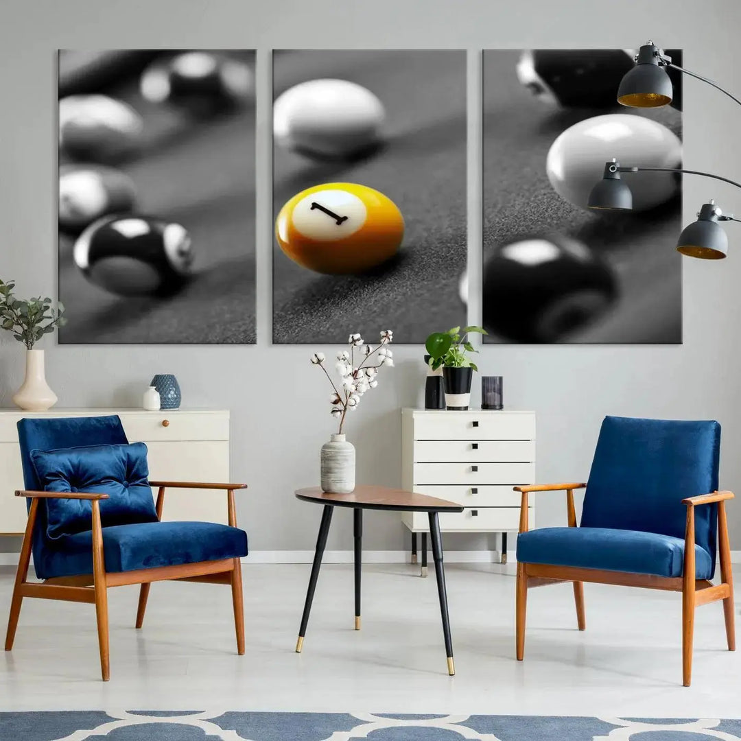 The modern living room features striking three-panel wall art titled "Black and White Concept Billiard Balls Canvas Print," showcasing a yellow number one ball on museum-quality canvas. This ready-to-hang piece is both stylish and convenient.