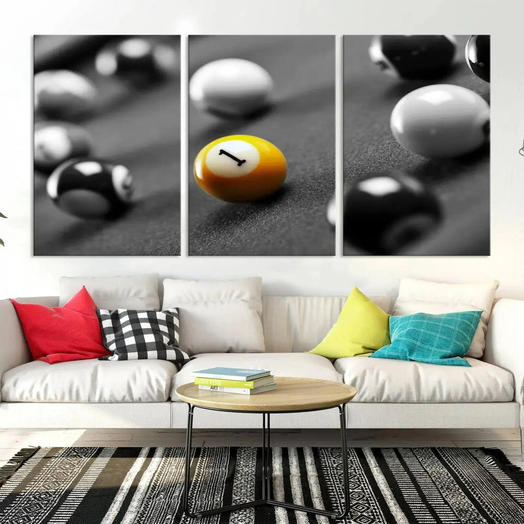 The modern living room features striking three-panel wall art titled "Black and White Concept Billiard Balls Canvas Print," showcasing a yellow number one ball on museum-quality canvas. This ready-to-hang piece is both stylish and convenient.