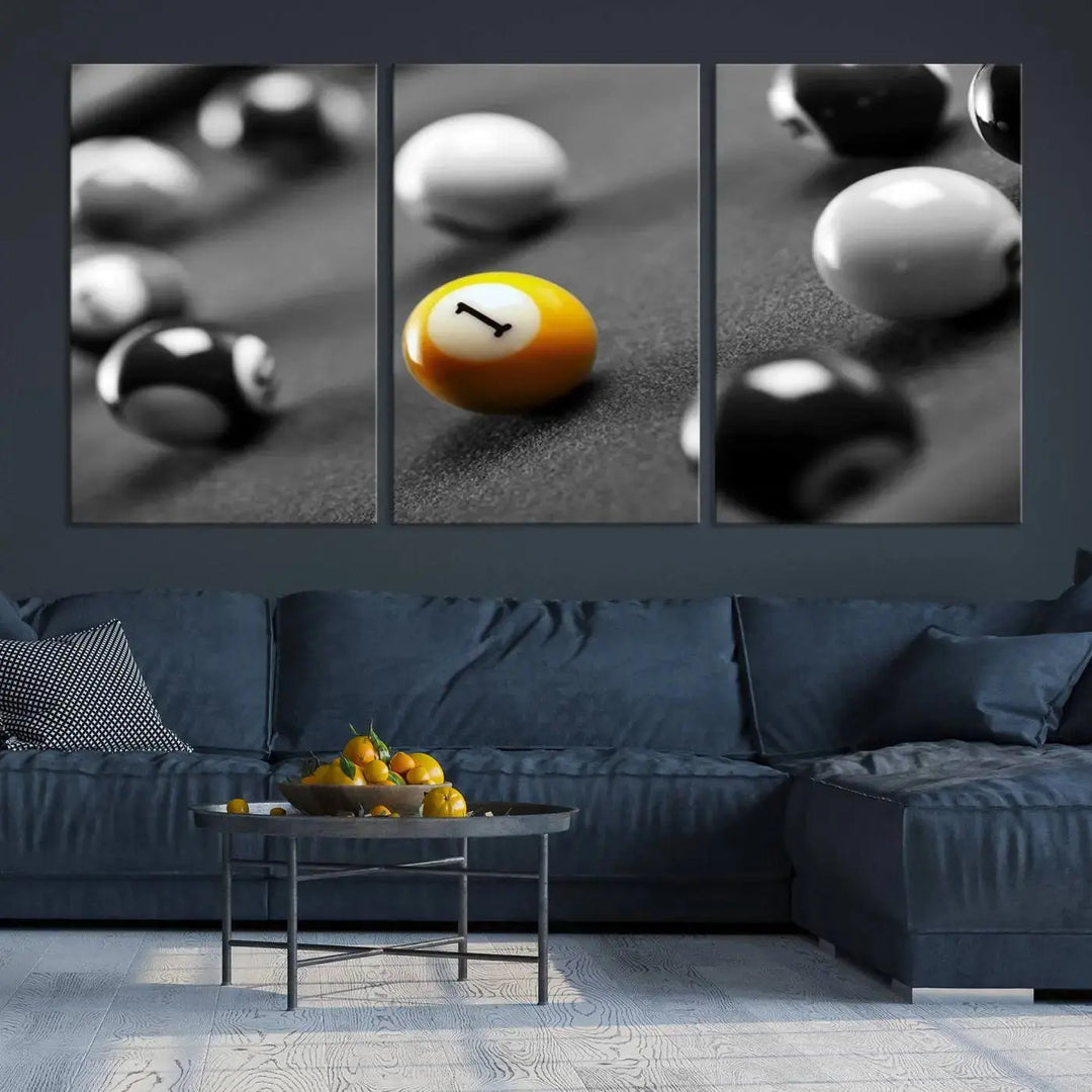 The modern living room features striking three-panel wall art titled "Black and White Concept Billiard Balls Canvas Print," showcasing a yellow number one ball on museum-quality canvas. This ready-to-hang piece is both stylish and convenient.