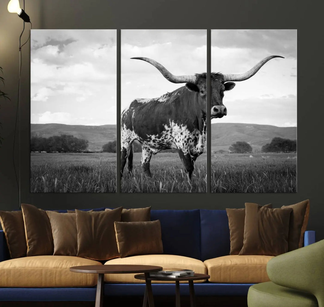 The Black and White Longhorn Texas Cow Canvas Wall Art Print showcases a striking longhorn cow with dramatic horns set against a grassy field in black and white on museum-quality canvas. Its UV-protective coating ensures enduring vibrancy, and it comes ready to hang, making it an ideal addition to an art enthusiast's space.