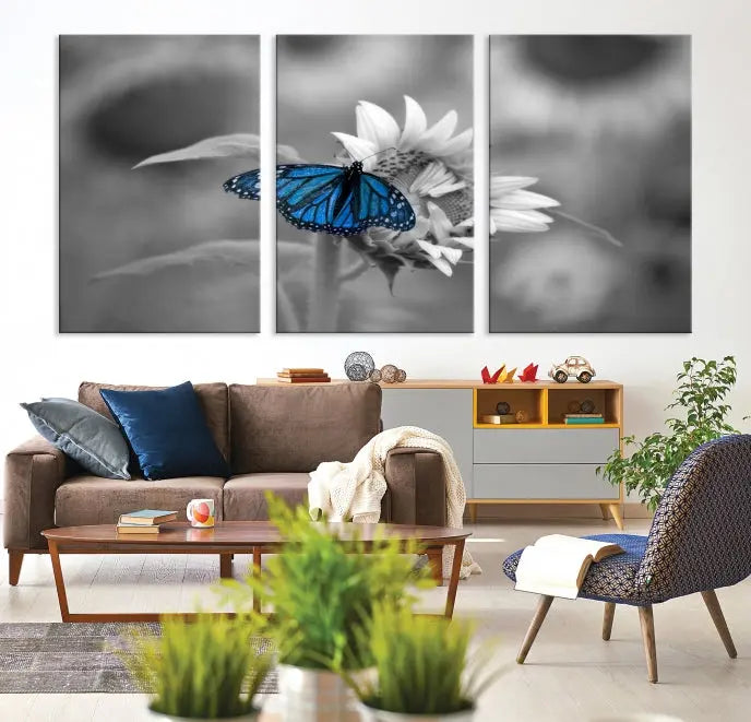 The modern living room showcases the Blue Butterfly Black and White Canvas Wall Art as a triptych. These museum-quality canvases, equipped with UV-protective coating and ready to hang, add both elegance and durability to the decor.