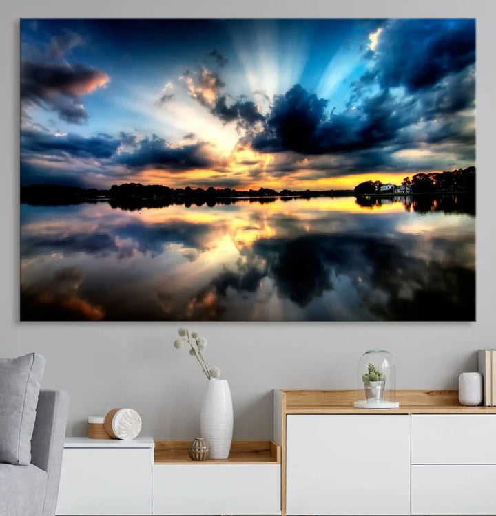 The "Blue Clouds and Sunshine Sunset Wall Art Canvas Print" perfectly captures a stunning sunset over a calm lake, where dramatic clouds and sunrays are beautifully reflected in the water. This museum-quality, ready-to-hang piece flawlessly preserves nature's breathtaking moment.