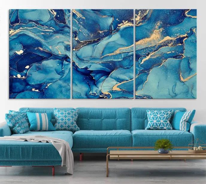 A contemporary living room features the "Blue Green Marble Abstract Canvas Wall Art Print," a triptych showcasing blue and gold abstract patterns on museum-quality canvas. This artwork includes a UV-protective coating for lasting vibrancy, making it ready to hang and transform any space.