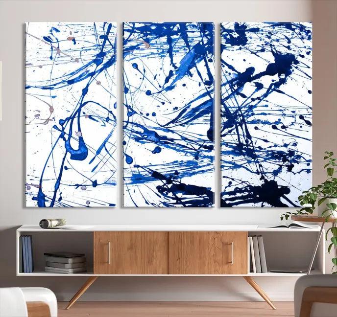 The Blue Ink Splash Wall Art Canvas Print Success is a triptych abstract piece featuring blue splatters on a clean white background. Crafted on gallery-wrapped canvases of museum quality, it includes a UV-protective coating to maintain its vibrant allure for years.