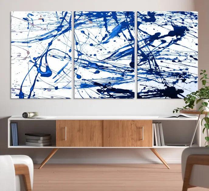 The Blue Ink Splash Wall Art Canvas Print Success is a triptych abstract piece featuring blue splatters on a clean white background. Crafted on gallery-wrapped canvases of museum quality, it includes a UV-protective coating to maintain its vibrant allure for years.