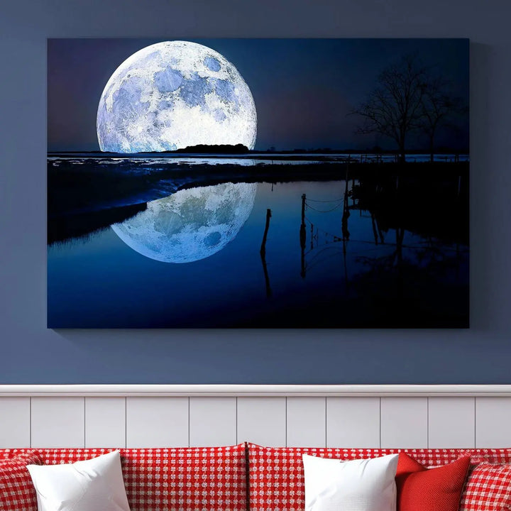 A mesmerizing Blue Moon Wall Art Canvas Print, depicting a lake landscape with a silhouetted tree, is beautifully presented on museum-quality canvas. This gallery-wrapped artwork, protected by a UV-coating to preserve its stunning details, stands out as an exquisite piece in the room.