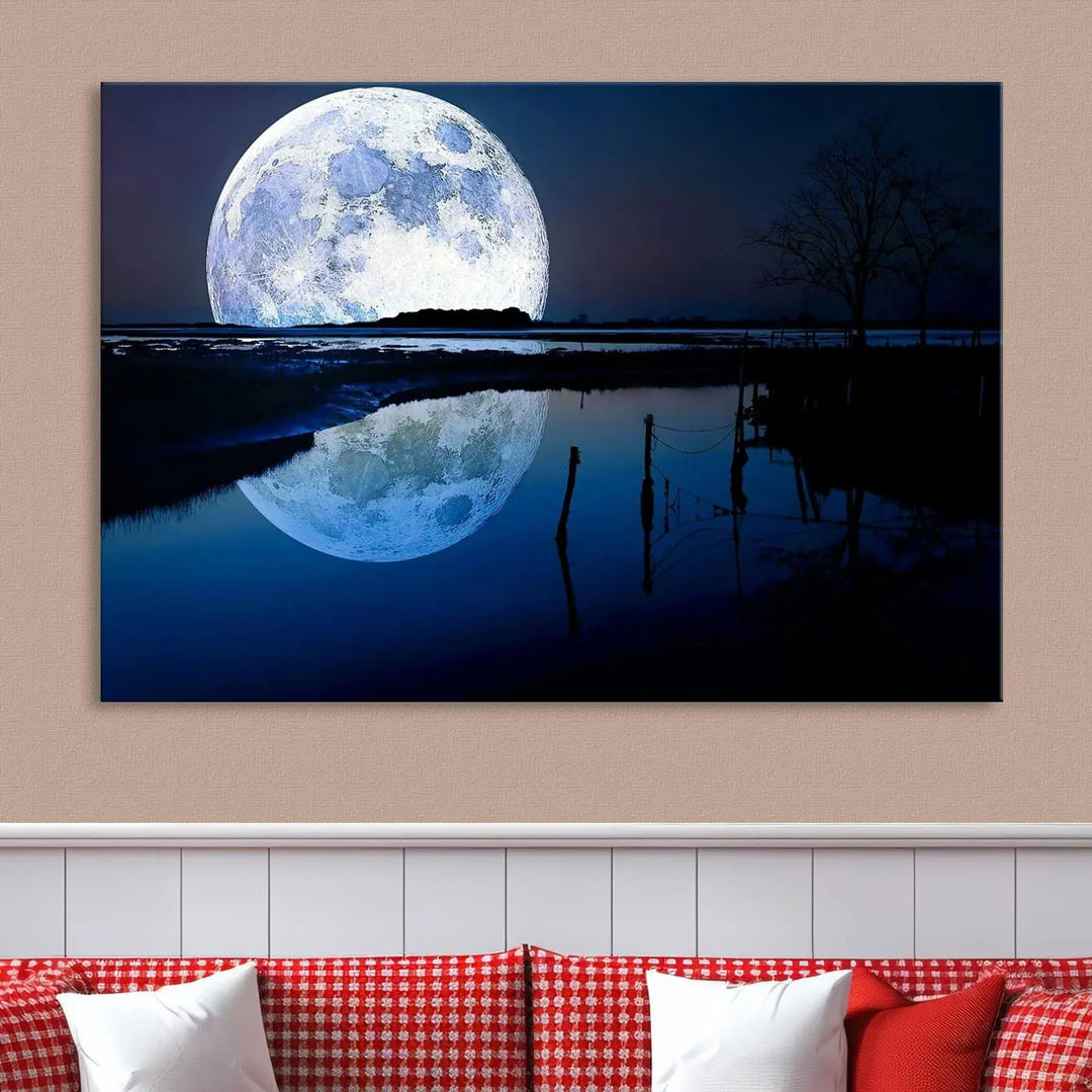 A mesmerizing Blue Moon Wall Art Canvas Print, depicting a lake landscape with a silhouetted tree, is beautifully presented on museum-quality canvas. This gallery-wrapped artwork, protected by a UV-coating to preserve its stunning details, stands out as an exquisite piece in the room.