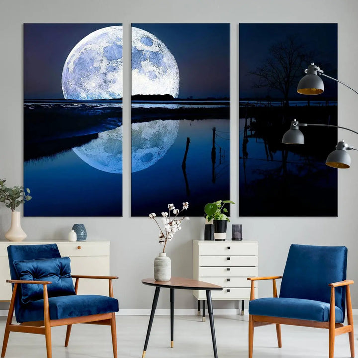 A mesmerizing Blue Moon Wall Art Canvas Print, depicting a lake landscape with a silhouetted tree, is beautifully presented on museum-quality canvas. This gallery-wrapped artwork, protected by a UV-coating to preserve its stunning details, stands out as an exquisite piece in the room.