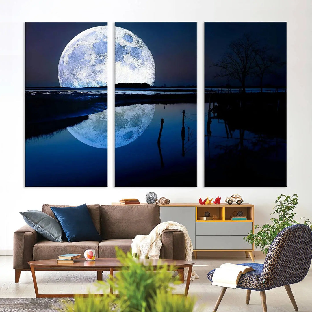 A mesmerizing Blue Moon Wall Art Canvas Print, depicting a lake landscape with a silhouetted tree, is beautifully presented on museum-quality canvas. This gallery-wrapped artwork, protected by a UV-coating to preserve its stunning details, stands out as an exquisite piece in the room.