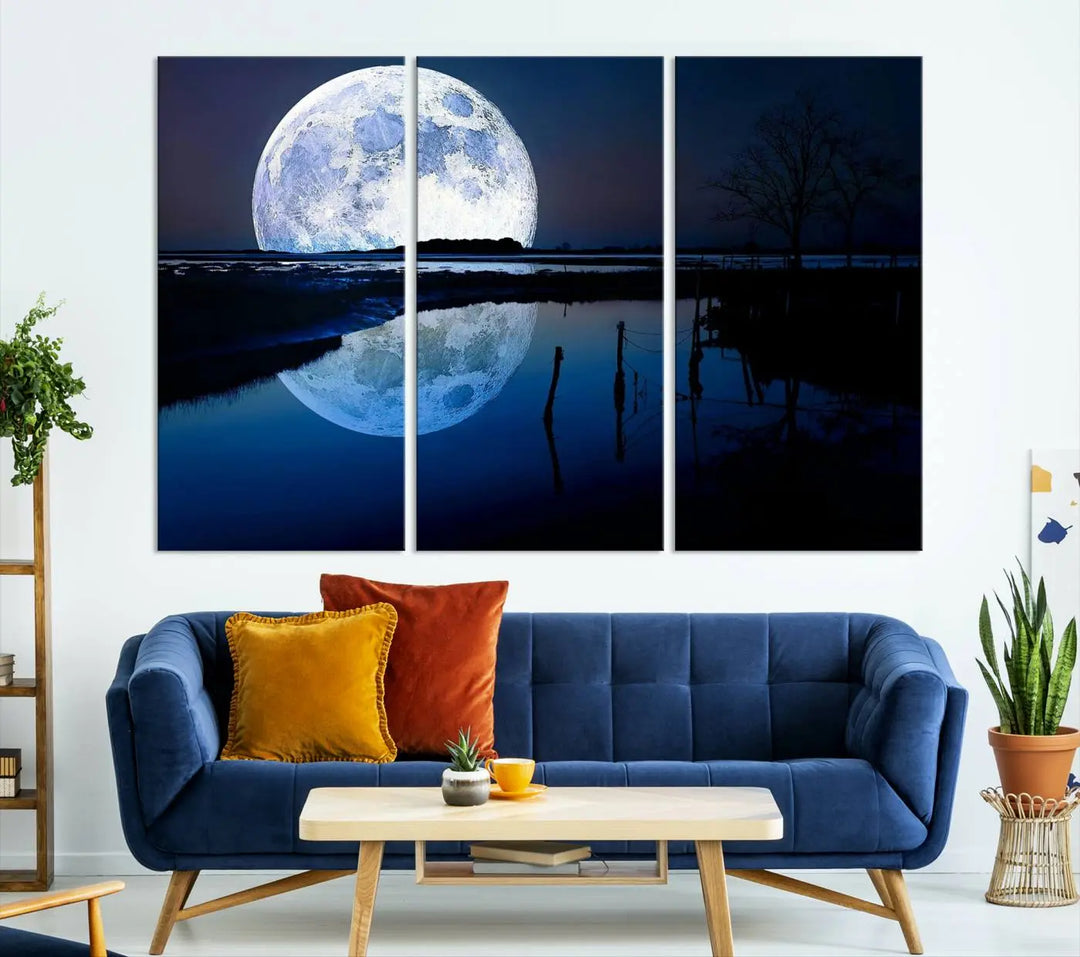 A mesmerizing Blue Moon Wall Art Canvas Print, depicting a lake landscape with a silhouetted tree, is beautifully presented on museum-quality canvas. This gallery-wrapped artwork, protected by a UV-coating to preserve its stunning details, stands out as an exquisite piece in the room.