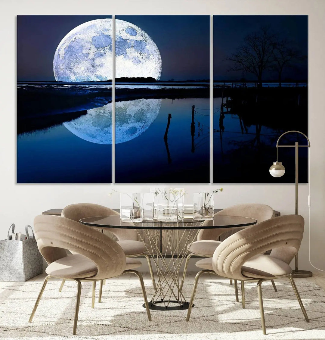 A mesmerizing Blue Moon Wall Art Canvas Print, depicting a lake landscape with a silhouetted tree, is beautifully presented on museum-quality canvas. This gallery-wrapped artwork, protected by a UV-coating to preserve its stunning details, stands out as an exquisite piece in the room.