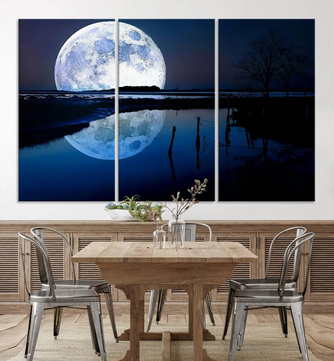 A mesmerizing Blue Moon Wall Art Canvas Print, depicting a lake landscape with a silhouetted tree, is beautifully presented on museum-quality canvas. This gallery-wrapped artwork, protected by a UV-coating to preserve its stunning details, stands out as an exquisite piece in the room.