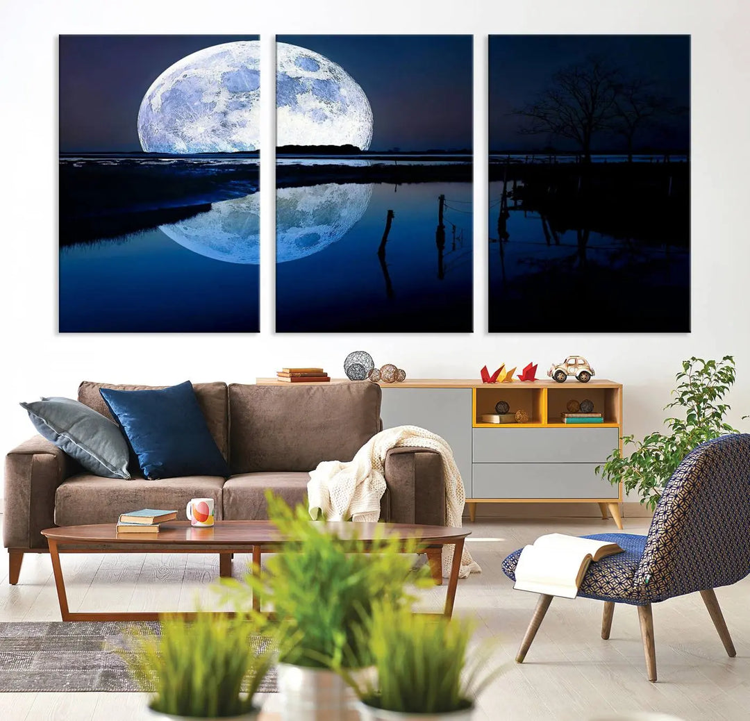 A mesmerizing Blue Moon Wall Art Canvas Print, depicting a lake landscape with a silhouetted tree, is beautifully presented on museum-quality canvas. This gallery-wrapped artwork, protected by a UV-coating to preserve its stunning details, stands out as an exquisite piece in the room.