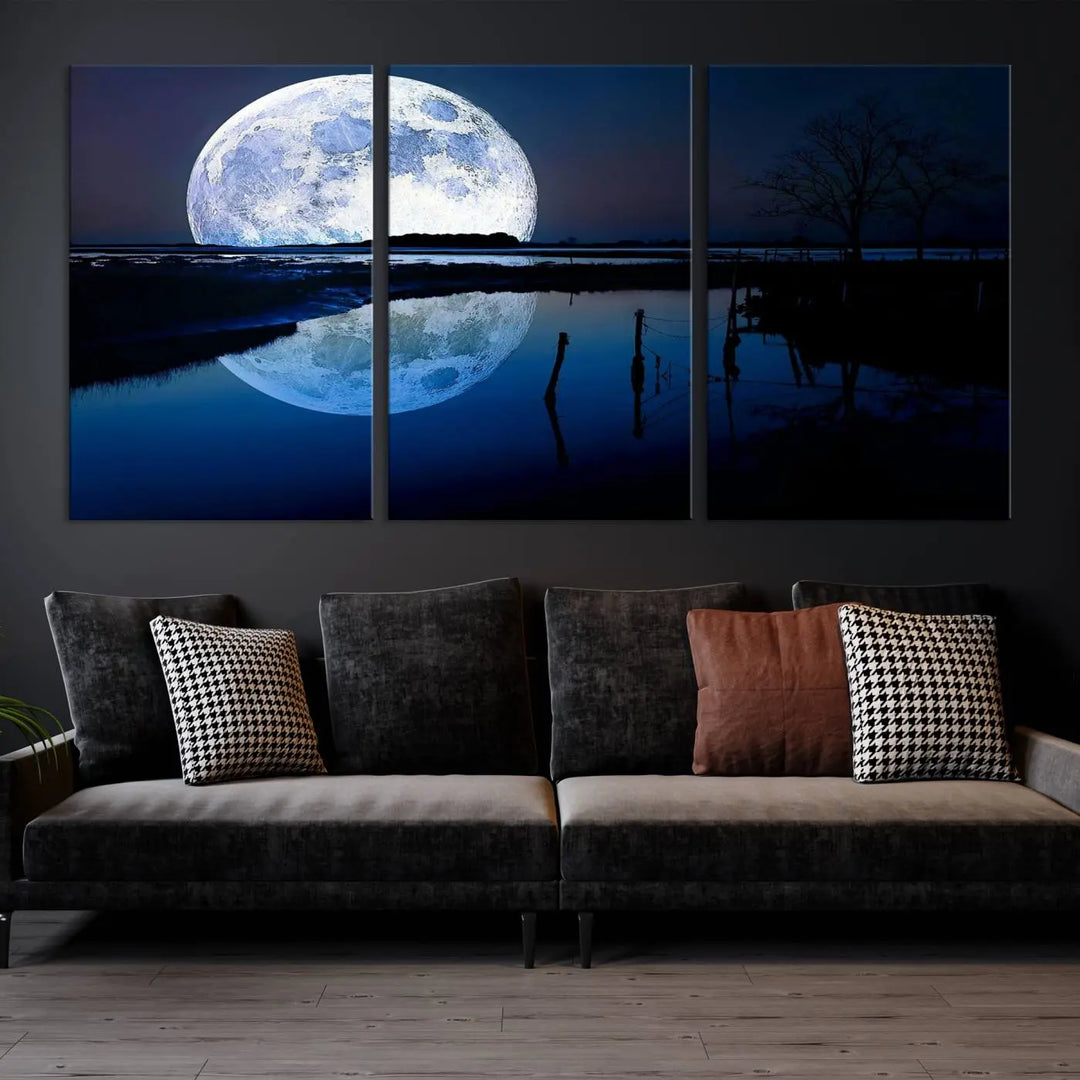 A mesmerizing Blue Moon Wall Art Canvas Print, depicting a lake landscape with a silhouetted tree, is beautifully presented on museum-quality canvas. This gallery-wrapped artwork, protected by a UV-coating to preserve its stunning details, stands out as an exquisite piece in the room.