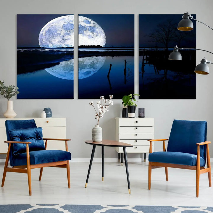 A mesmerizing Blue Moon Wall Art Canvas Print, depicting a lake landscape with a silhouetted tree, is beautifully presented on museum-quality canvas. This gallery-wrapped artwork, protected by a UV-coating to preserve its stunning details, stands out as an exquisite piece in the room.